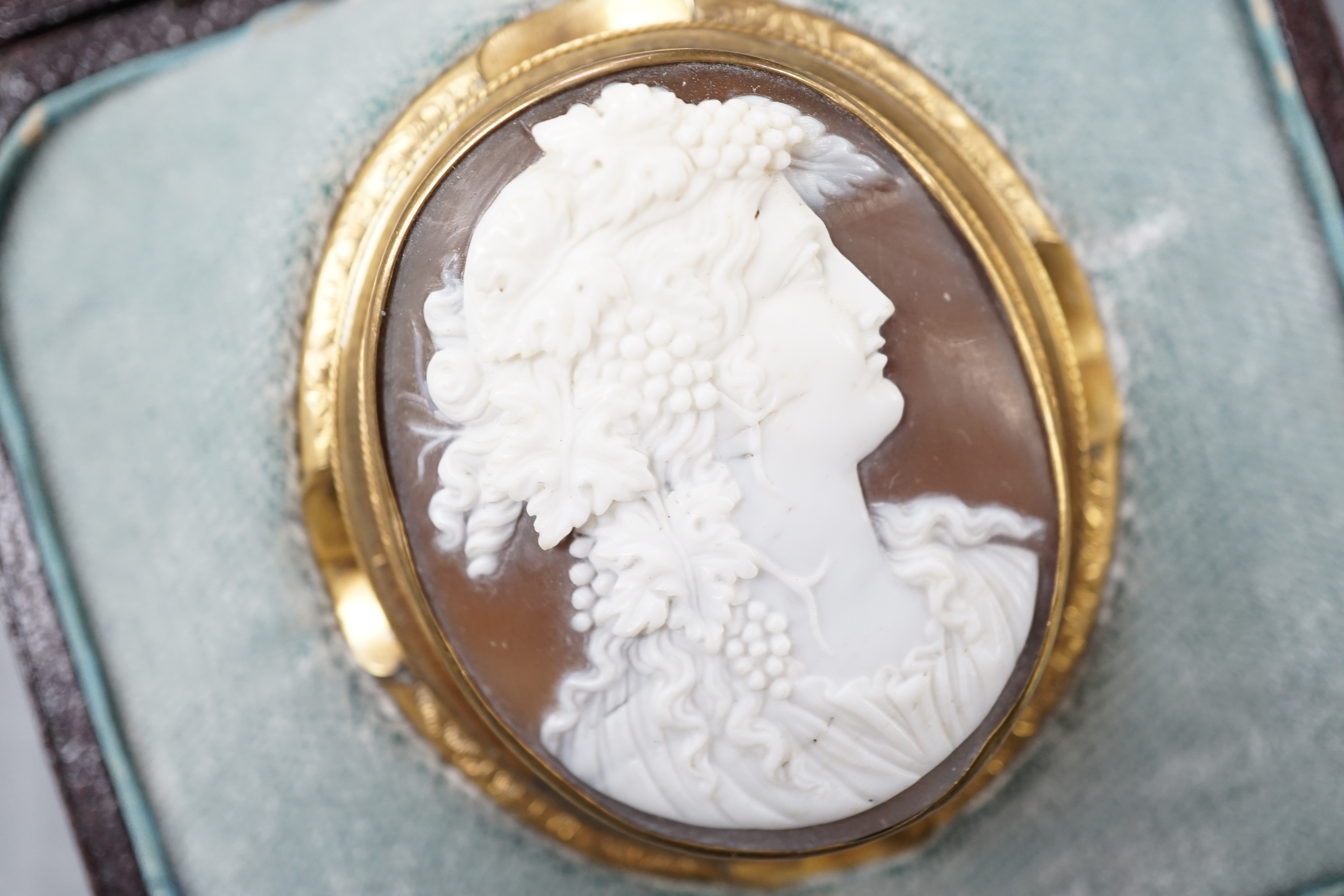 A cased Victorian yellow metal mounted oval cameo shell brooch, carved with the bust of a lady to sinister, 50mm, gross 15.6 grams.